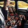 A woman sits in a car, holding a black and orange patchwork Halloween throw blanket with pumpkin and moon prints.