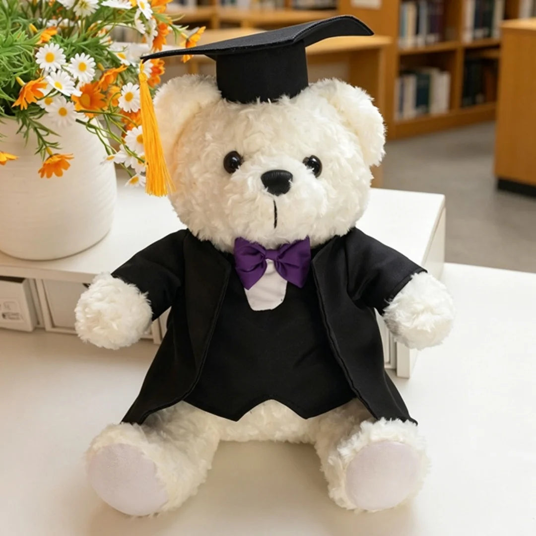 Peluche d'ours docteur diplômé portant une toque noire et un nœud papillon violet.