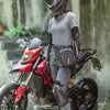 A person wearing a black motorcycle helmet and black gloves stands next to a red motorcycle with a black hip pack.