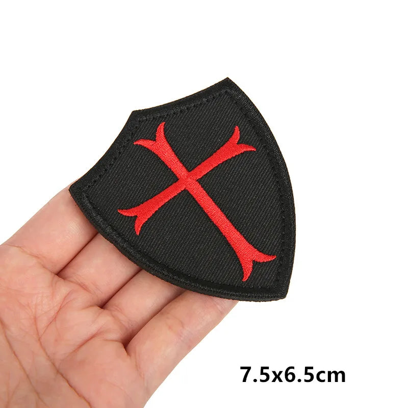 Black embroidered patch featuring a red cross design with hook and loop backing