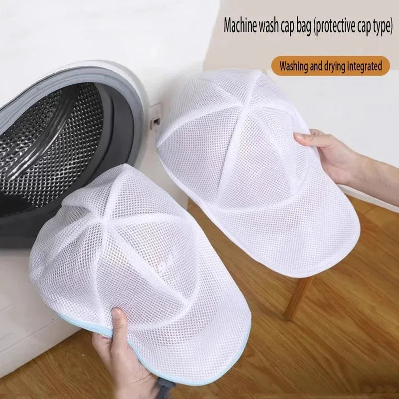 A white mesh laundry bag designed for protecting hats and delicate clothing, shown next to a washing machine.