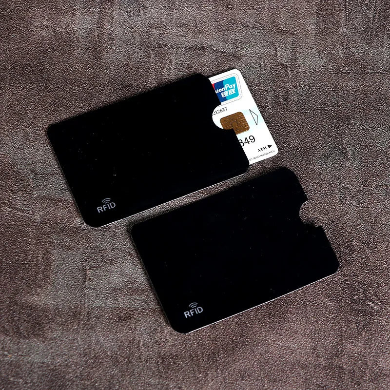 A set of black RFID blocking card sleeves and a UnionPay card are displayed on a brown textured surface.