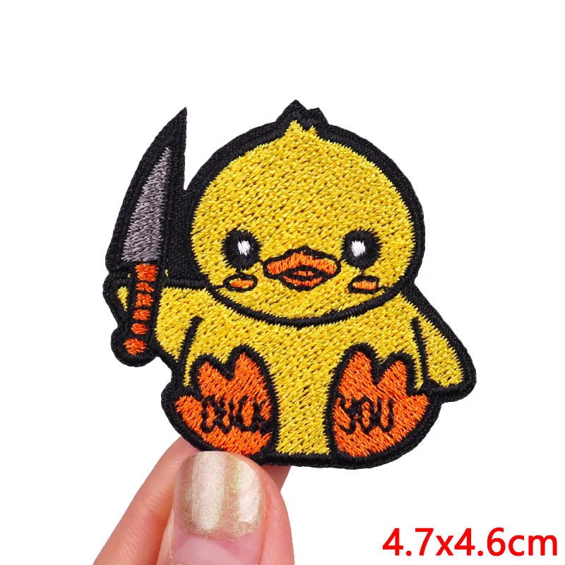 A yellow cartoon chick embroidered patch with a black beak and wings on a finger.