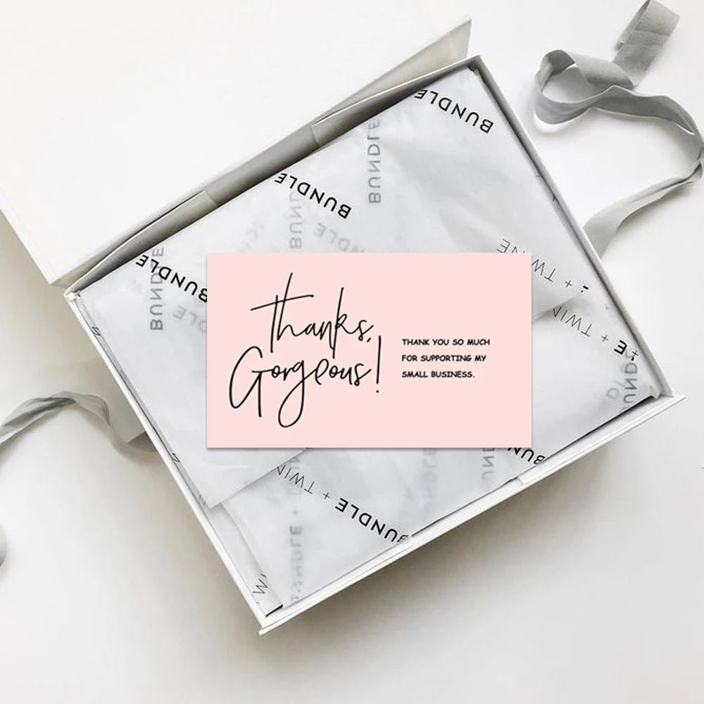 A small square greeting card with handwritten text saying thanks gorgeous to support my small business is shown in a light pi