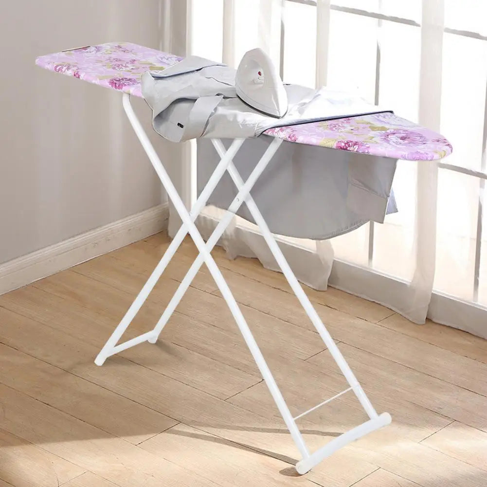 A white foldable ironing board with a purple floral cover is shown next to a window.