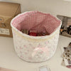 Cesta de almacenamiento con forma de corazón acolchada blanca, forrada con tela a cuadros rosa, que contiene frascos y artícu