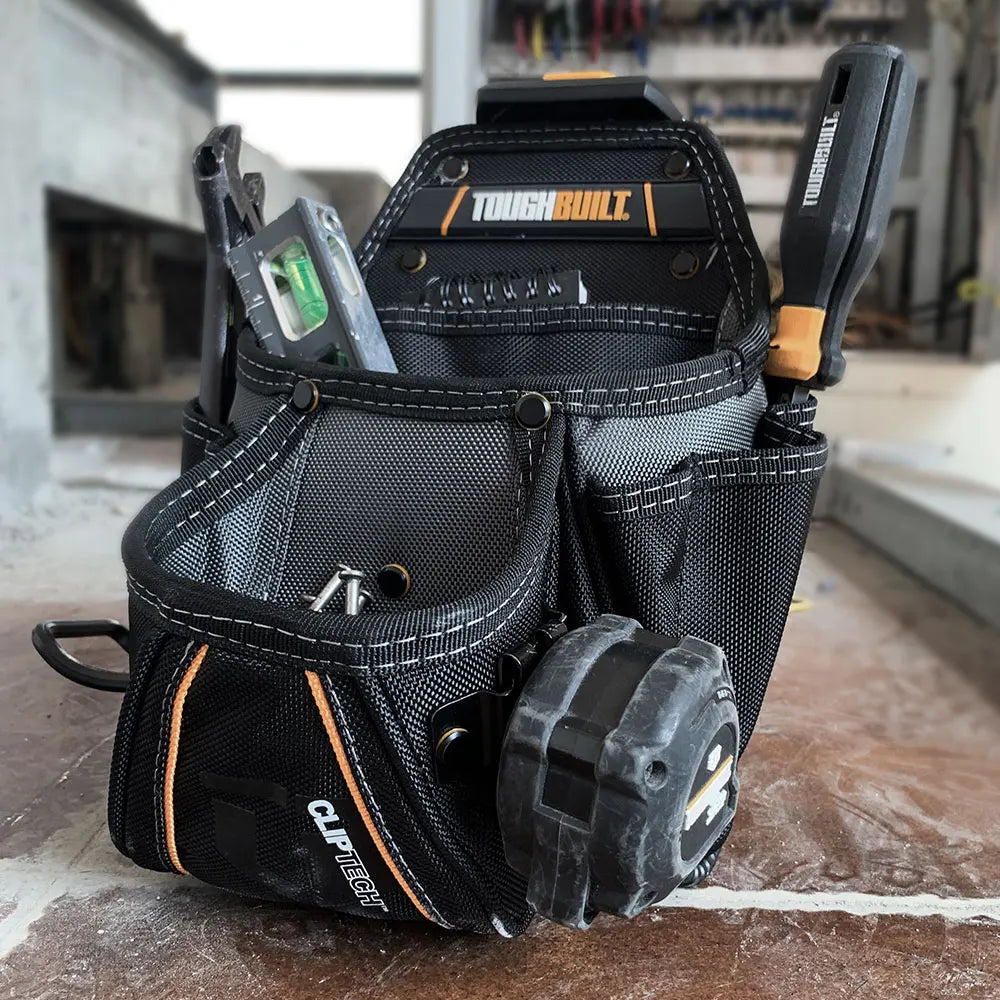 A black heavy-duty construction tool pouch featuring a ClipTech hub and hammer loop resting on a wooden surface.