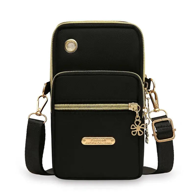 Bolso cruz impermeable de nylon negro con detalles dorados y cierre de solapa.