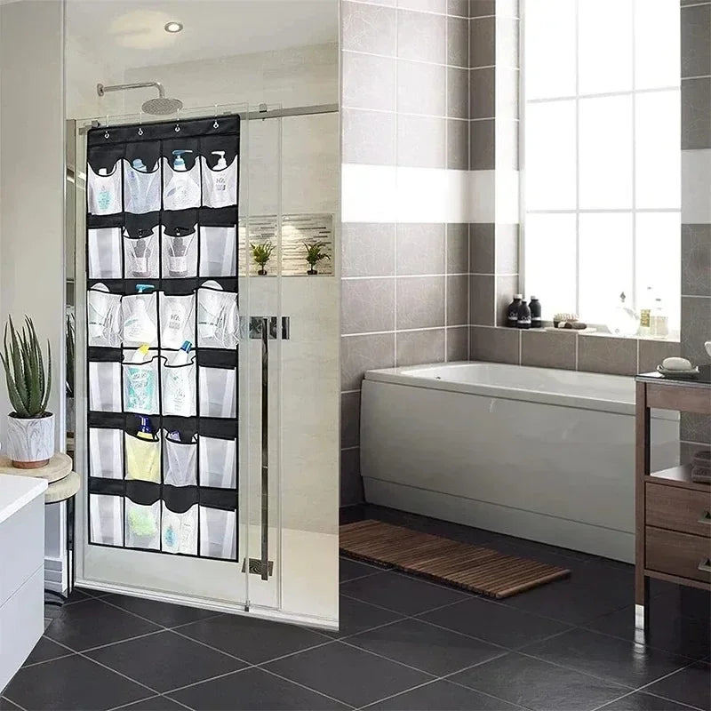 A white over-the-door mesh shoe organizer with hanging pockets is mounted on a glass door in a modern bathroom.