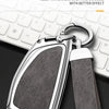A silver key chain with a leather strap and metal clasp resting on a white computer keyboard.