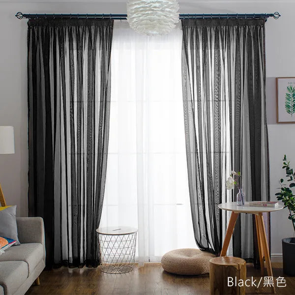 Black sheer voile curtains with a rod pocket filtering light in a bright room.