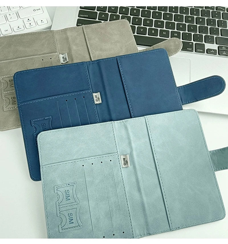 Un juego de tres carteras de pasaporte en cuero gris, azul y verde menta con tecnología RFID blocking.