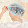 A woman is wearing a light blue sheer shower cap with white polka dots and a striped shirt.