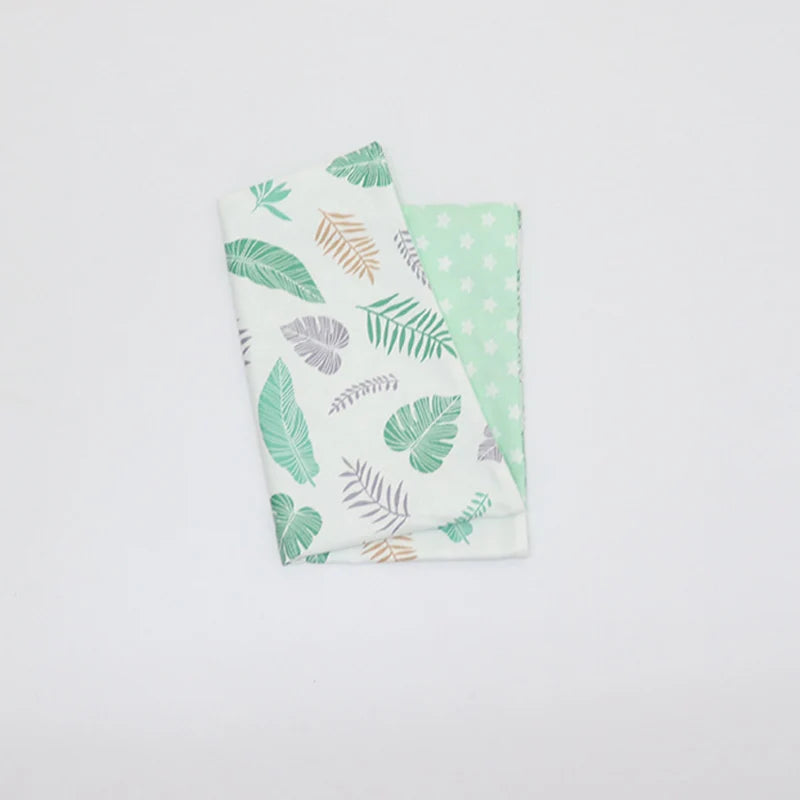 A folded soft cotton baby pillowcase featuring a pattern of green and beige leaf designs.