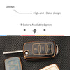 A close-up view of a brown TPU silicone car key case with a key inserted, displayed on a black textured surface.