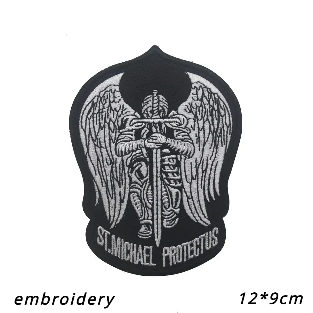 Black embroidery of an archangel with wings and a sword, featuring the text St. Michael Protectus.