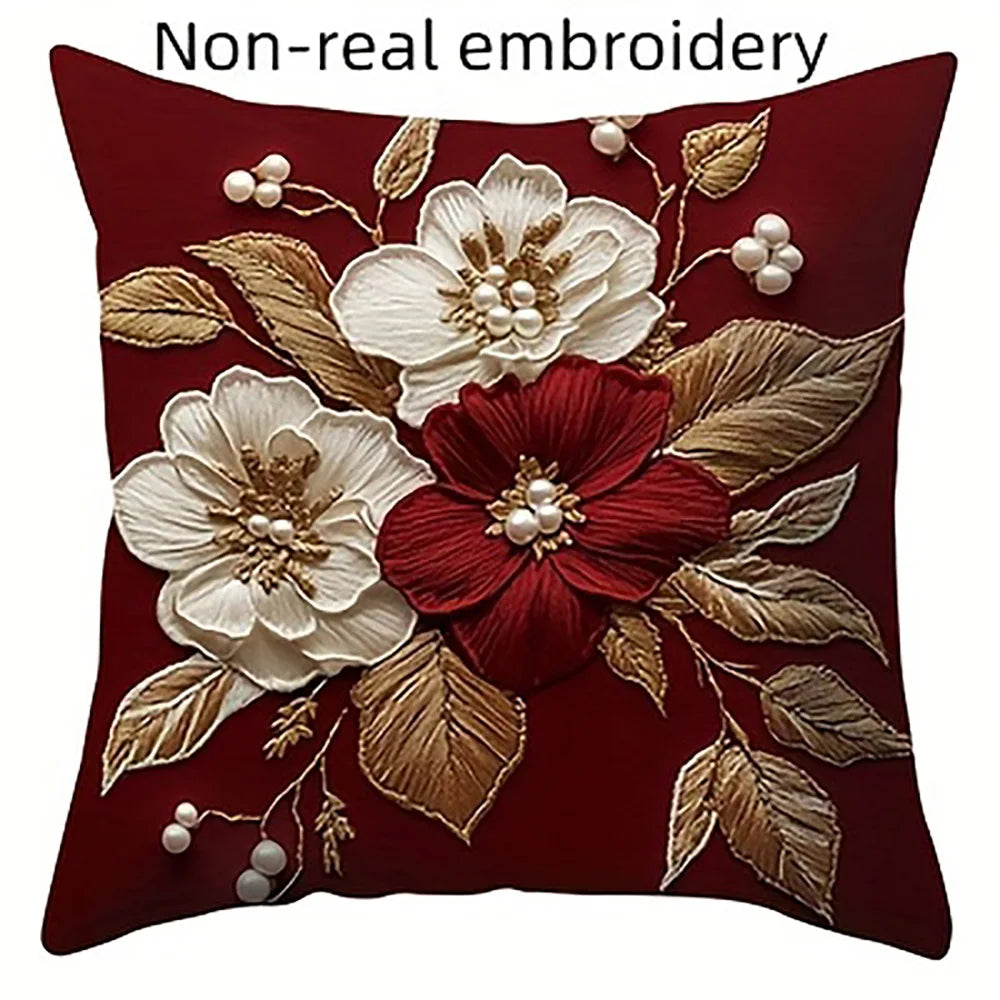 A deep red pillow featuring non-real embroidery of white and maroon flowers and leaves.