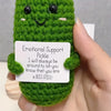 Handcrafted pickle plush toy with a green textured body and black eyes and a smiling mouth.
