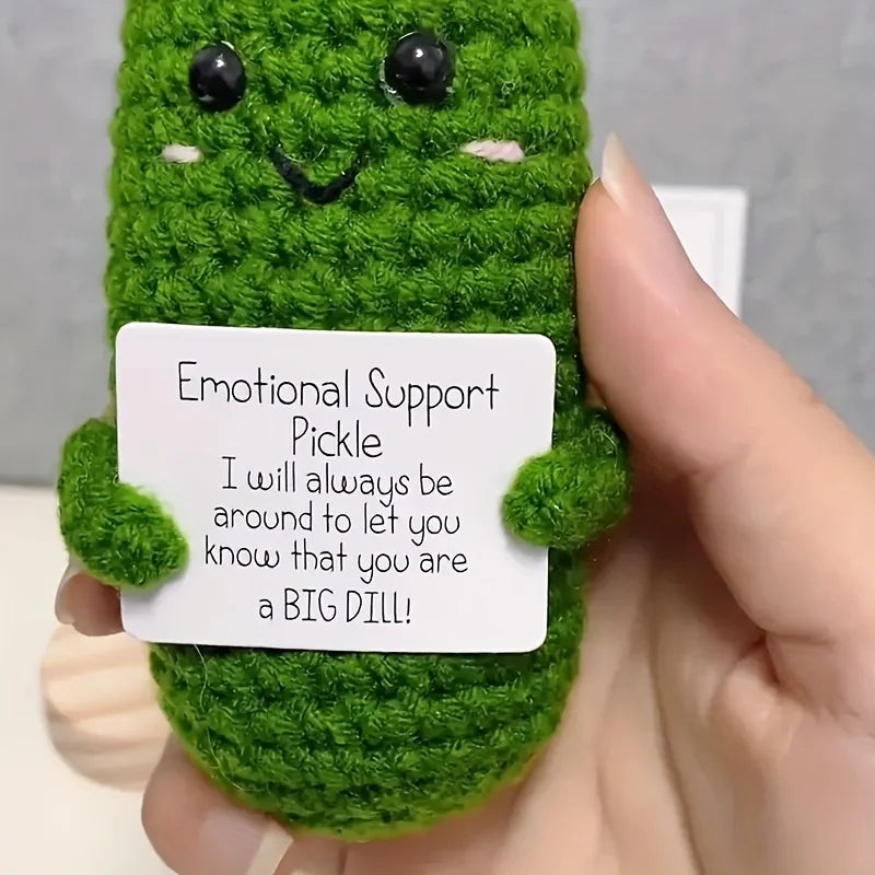 Handcrafted pickle plush toy with a green textured body and black eyes and a smiling mouth.