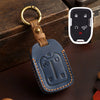 A dark blue leather key fob case with a brass ring attached, shown next to a white electronic key fob.