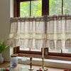 Beige gingham cafe curtain with crochet lace trim hanging in a window.