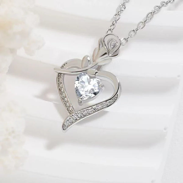 A silver heart pendant necklace featuring a clear diamond-cut heart centerpiece and delicate detailing.