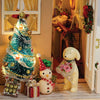 A festive Christmas tree decorated with lights and ornaments sits next to a yellow rubber duck and gift boxes.