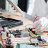 A close-up view of a multimeter back-piercing test probe kit with various needle tips resting on a circuit board.