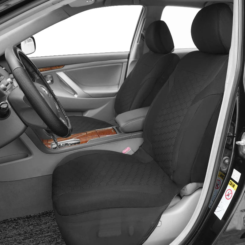 A black car seat covered with a honeycomb mesh fabric inside a vehicle cabin.
