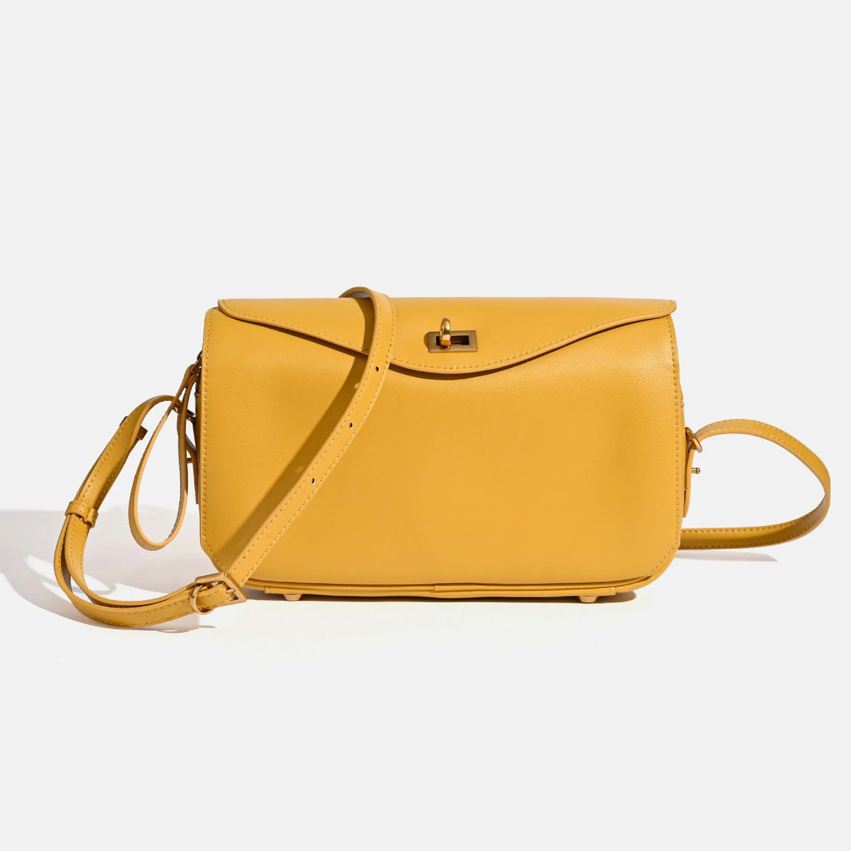 A yellow genuine leather square crossbody bag with a gold lock and strap.
