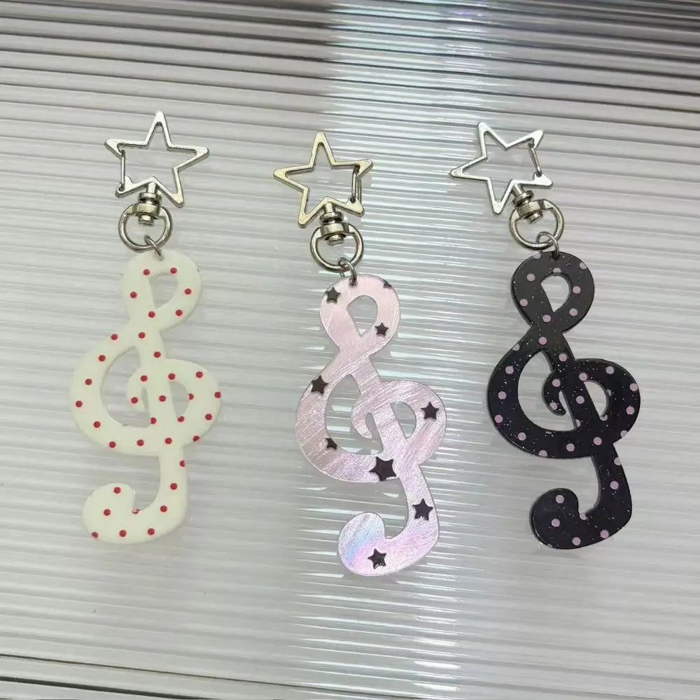 Trois porte-clés en acrylique en forme de notes de musique, dans des designs de clé de sol et de clé de fa
