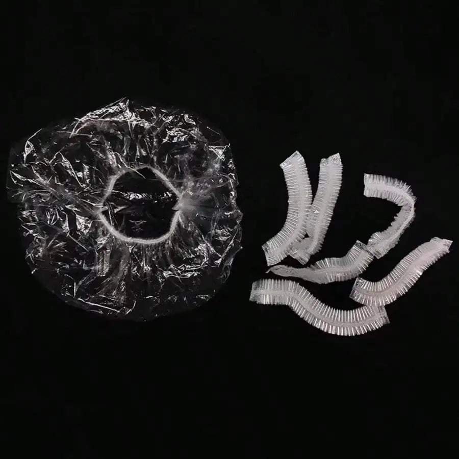 A pile of disposable transparent shower caps, packaged in clear plastic, is shown next to several loose caps.