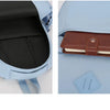A light blue nylon backpack showing the interior compartment and an exterior leather wallet.