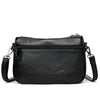 Black leather compact square crossbody bag with a zippered top and a chain strap.