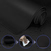 Black extended anti-slip desk pad with stitched edges shown rolled and being touched