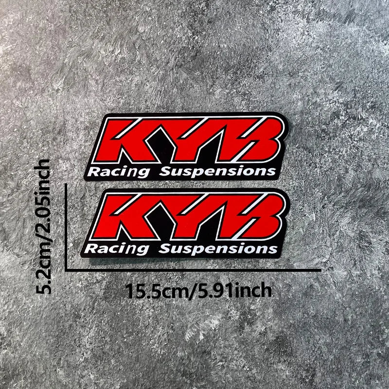 Two black and red decals featuring the KYB Racing Suspensions logo on a gray textured background.