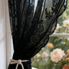 Black vintage floral lace sheer curtains tied with twine hanging in a window