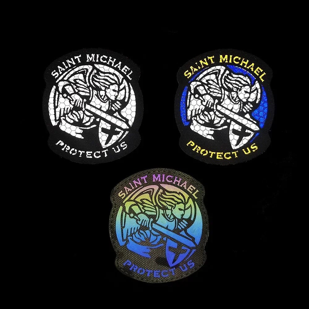 Three round patches featuring the archangel Saint Michael with a sword and the text Protect Us on black and blue backgrounds.