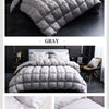 A gray quilted duvet and bedding set displayed on a bed in a modern bedroom setting.