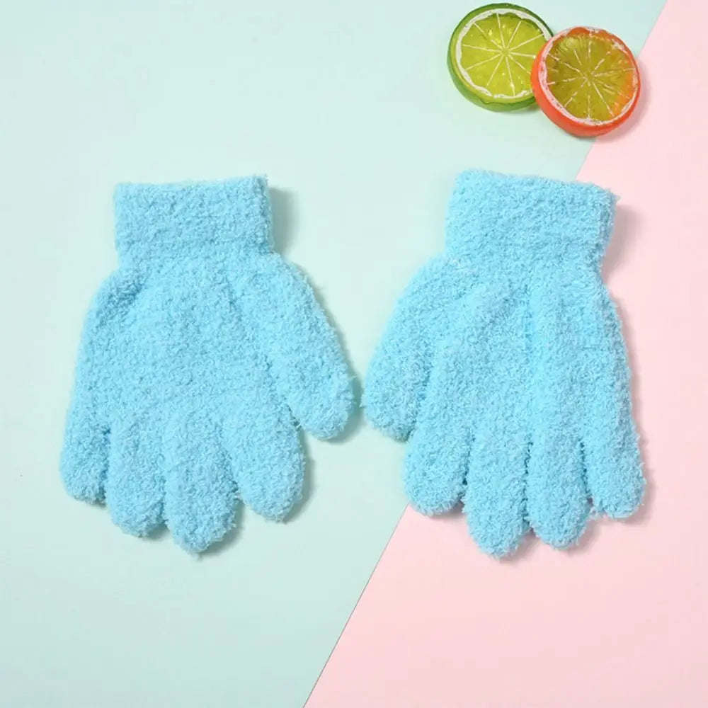 Pair of light blue fuzzy plush winter gloves for kids with a slice of lime nearby