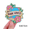 A colorful embroidery patch featuring the text BOOK LOVER surrounded by floral elements.