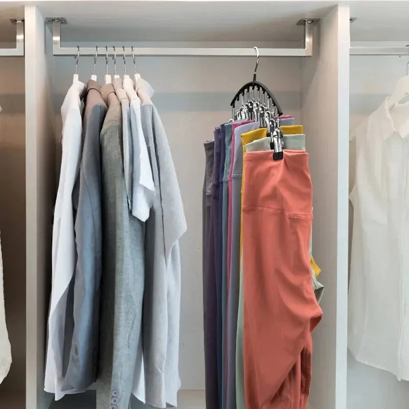 A display of various colored pants hanging on a metal hanger rack in a closet or wardrobe.