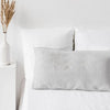 A white linen pillowcase with an envelope closure resting on a white bed.