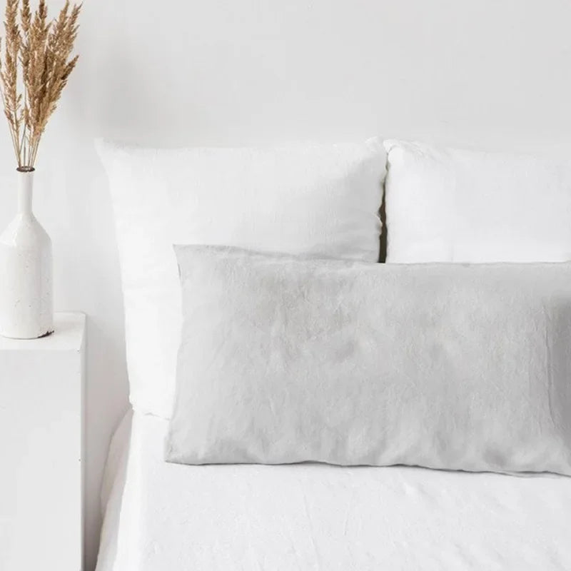 A white linen pillowcase with an envelope closure resting on a white bed.