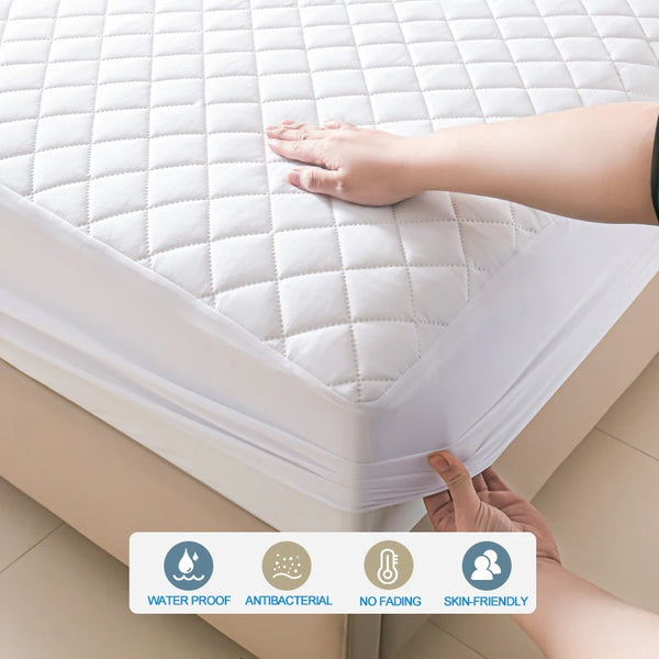 A hand is touching a white quilted mattress protector, highlighting its waterproof and antibacterial features.