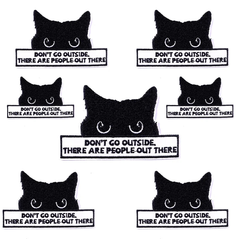 Ten black cat face patches embroidered with text warning not to go outside because there are people out there