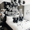 A black and silver balloon garland featuring oversized foil numbers on a bed backdrop.