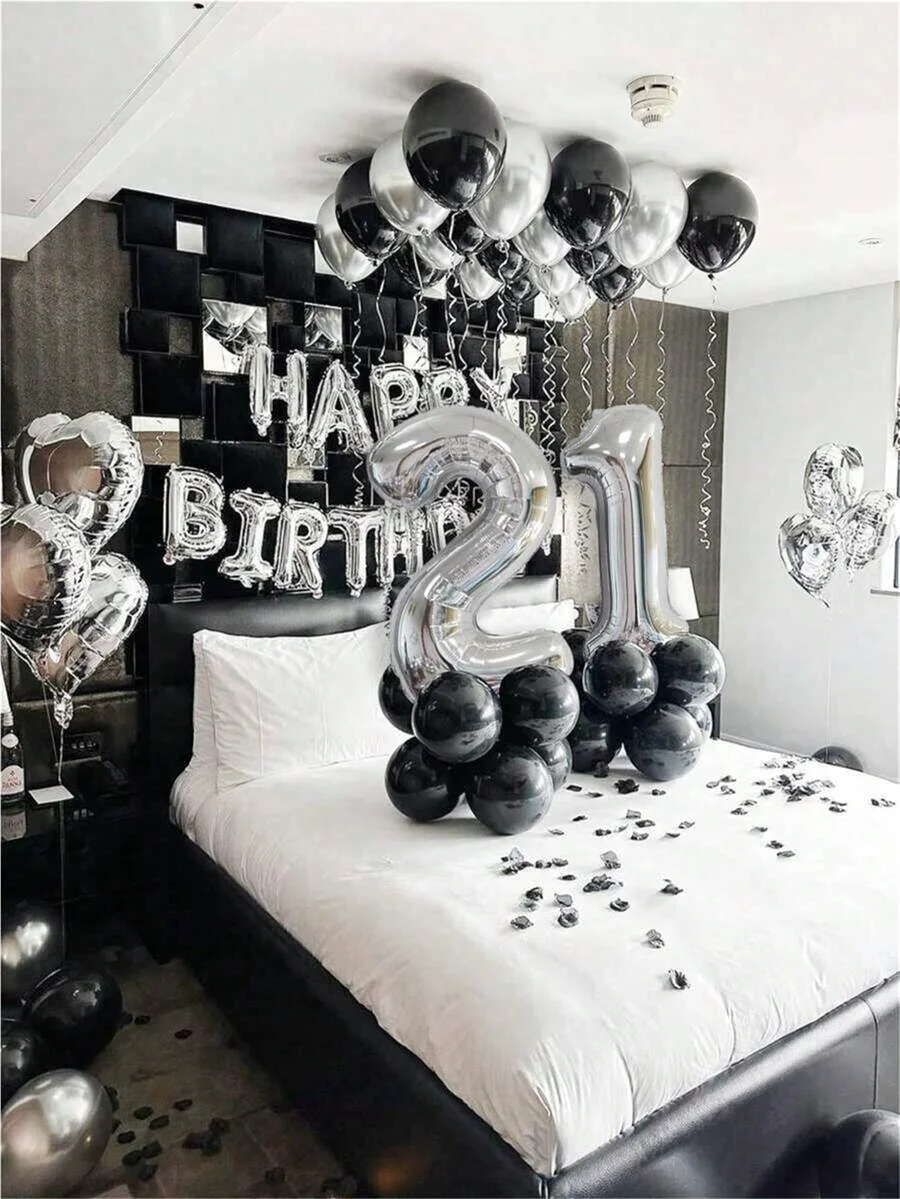 A black and silver balloon garland featuring oversized foil numbers on a bed backdrop.