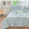 A light blue pastoral print lightweight summer quilt displayed on a bed with white and natural wood accents.