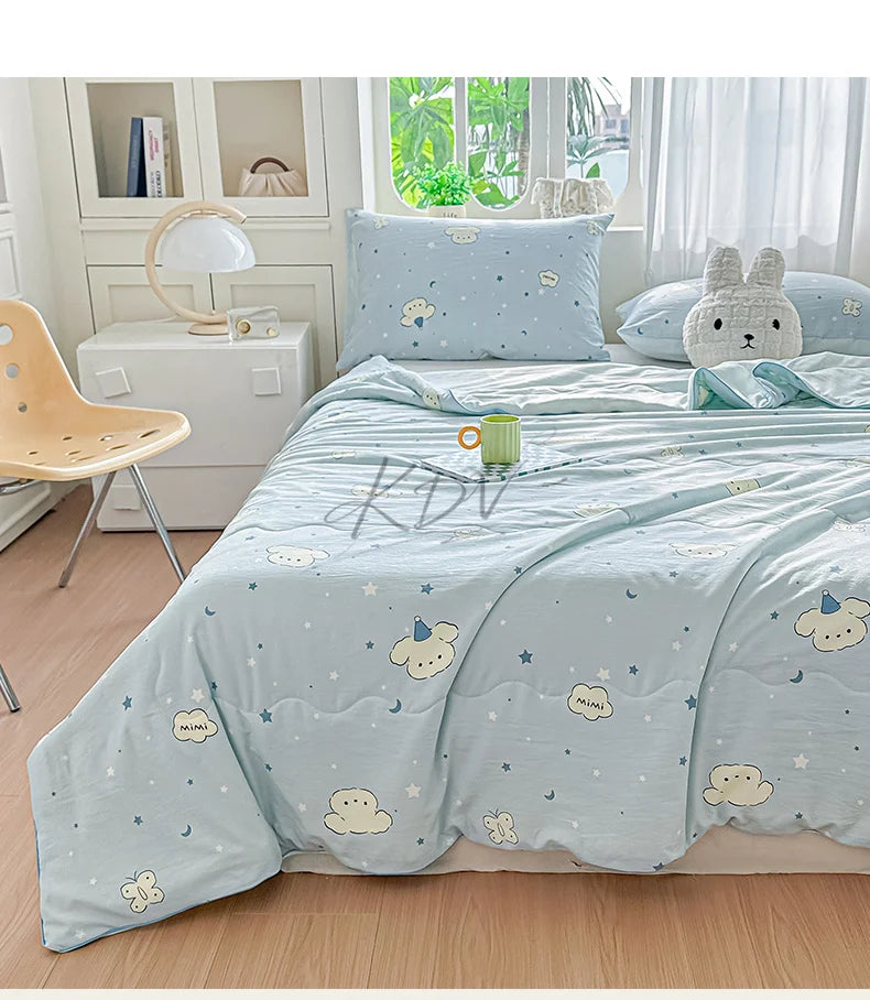 A light blue pastoral print lightweight summer quilt displayed on a bed with white and natural wood accents.